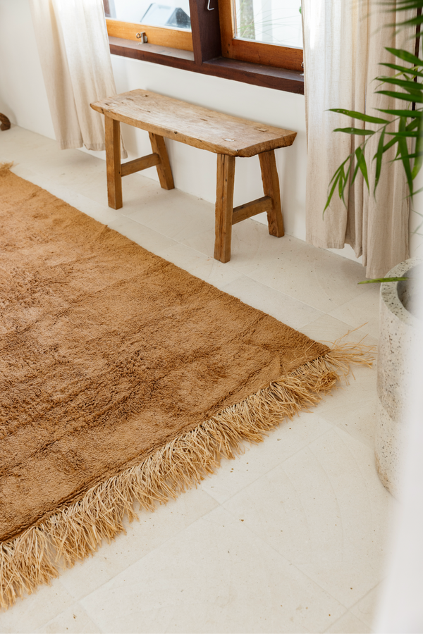 Textured tan rug with fringe detailing placed in a bright room